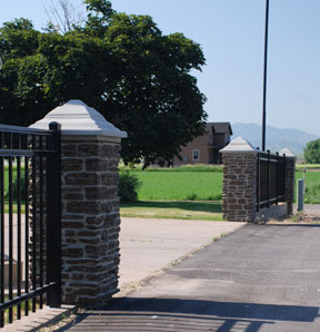 Faux rock pillar with ornamental fence